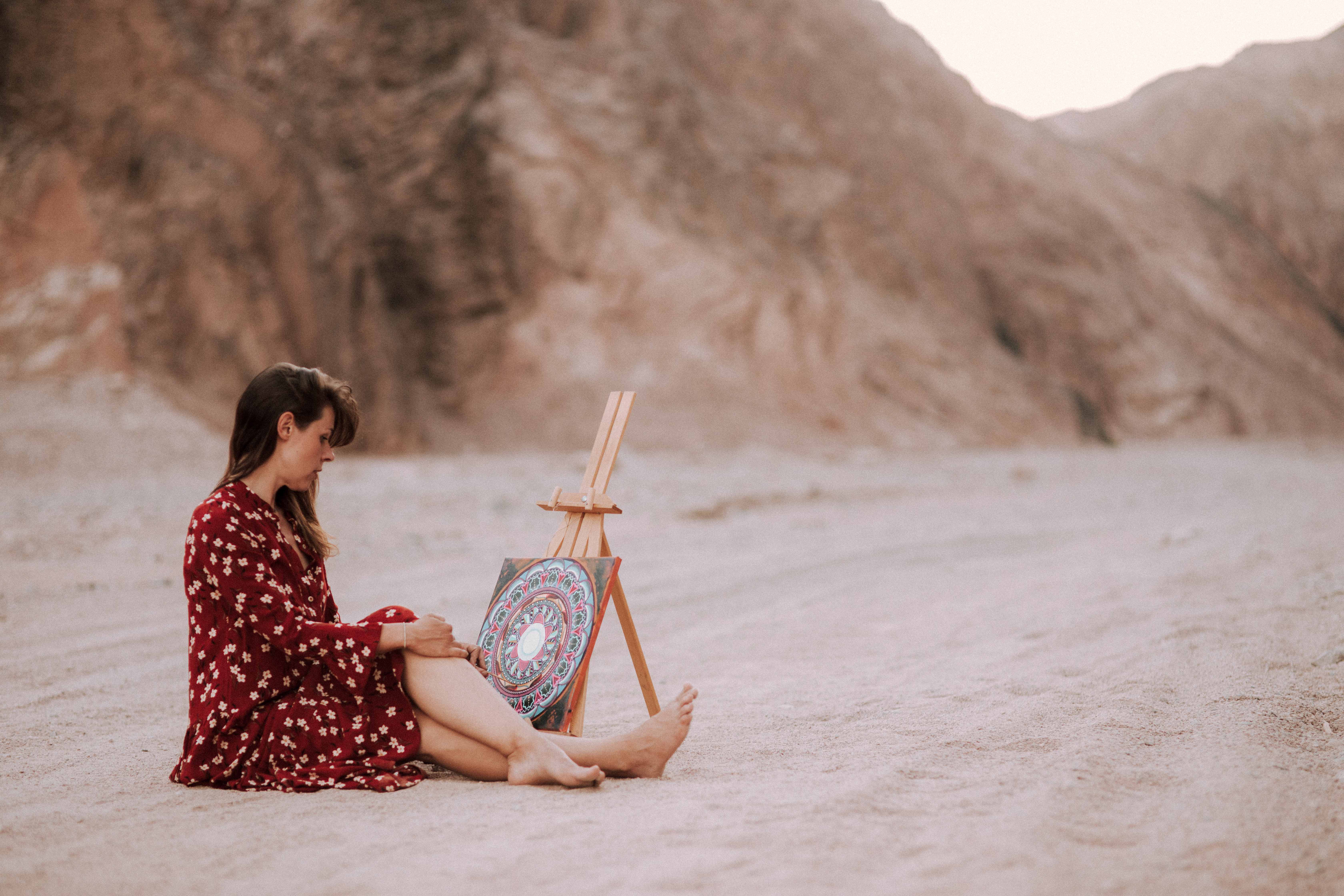 Ela sitting with mandala on easel in desert canyon