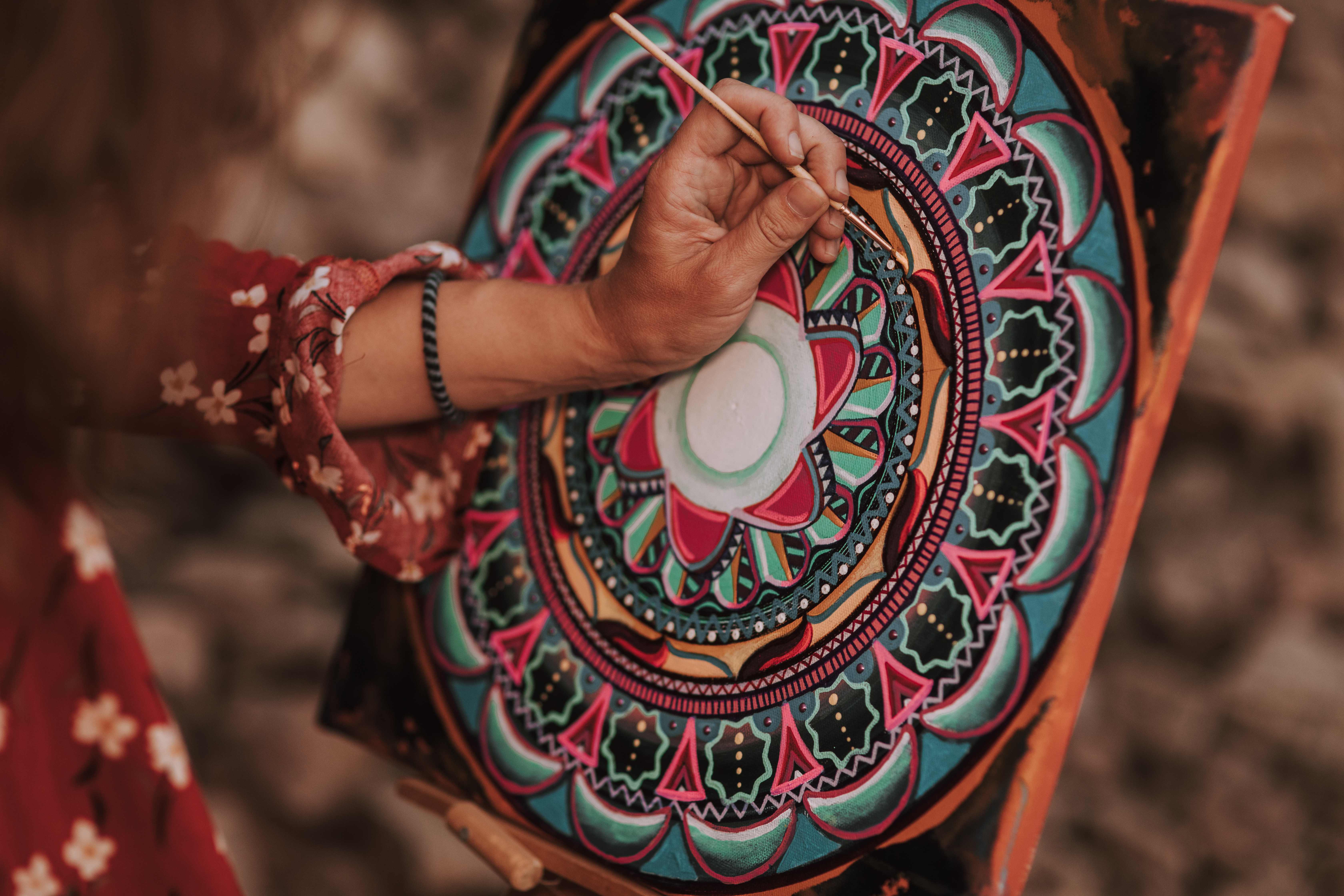 Hands painting mandala on canvas
